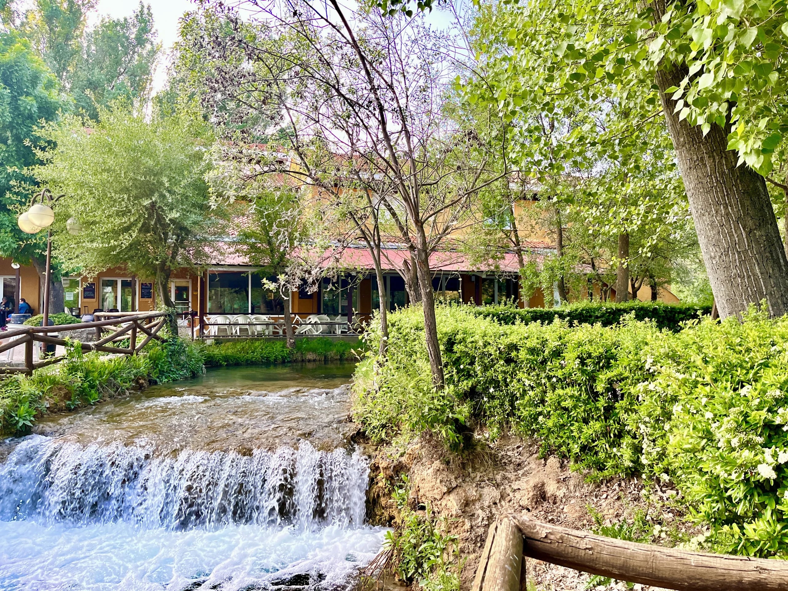 Terraza del hostal junto a una cascada del río, rodeada de arboleda