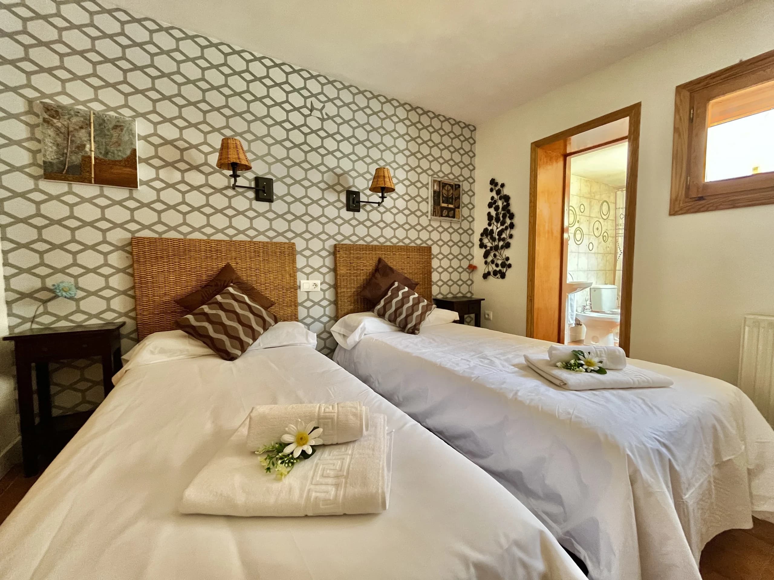Habitación con dos camas individuales vestidas en blanco y detalles en madera